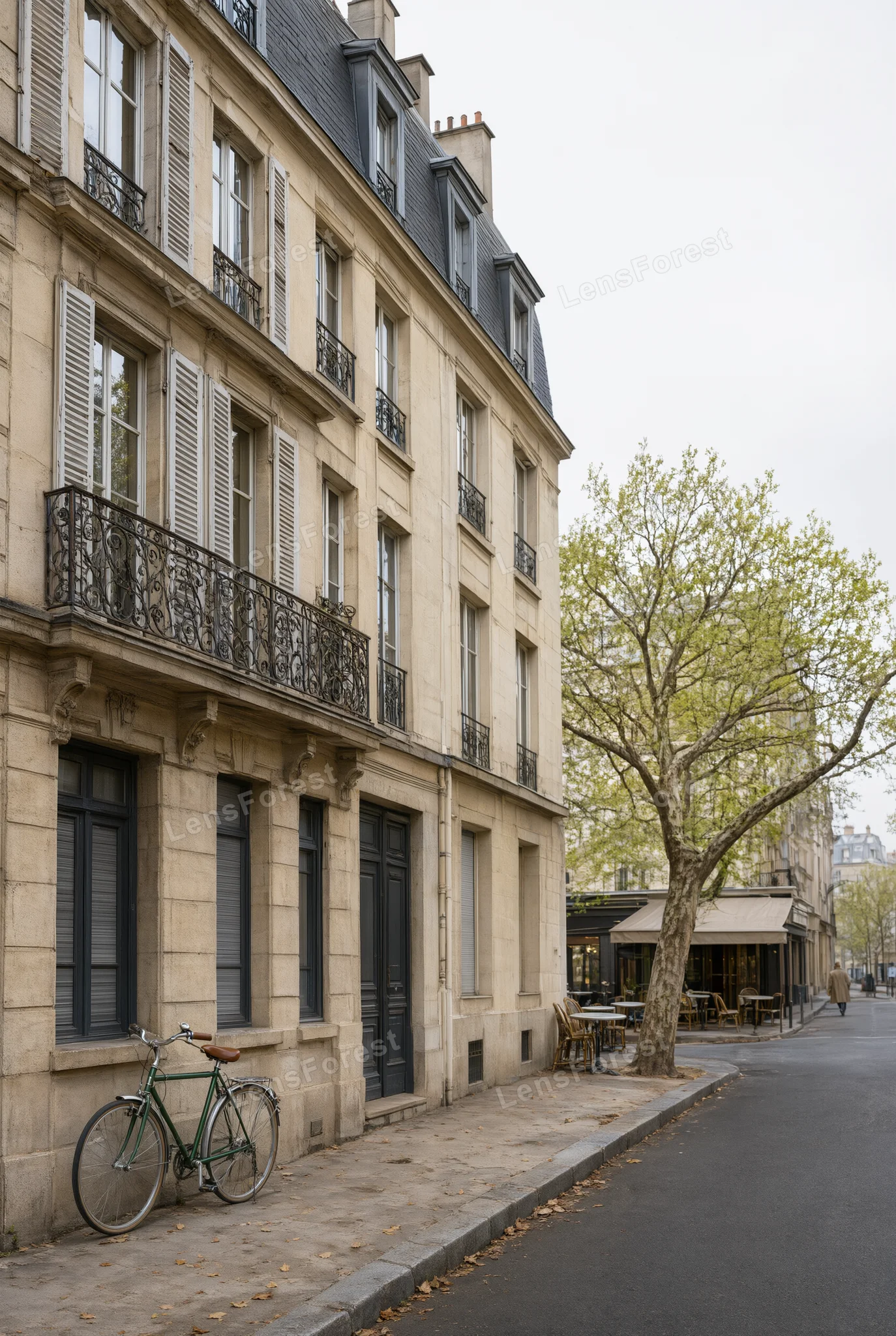 A green bicycle parked on a sidewalk in front of a historic stone building with iron balconies and wooden shutters.