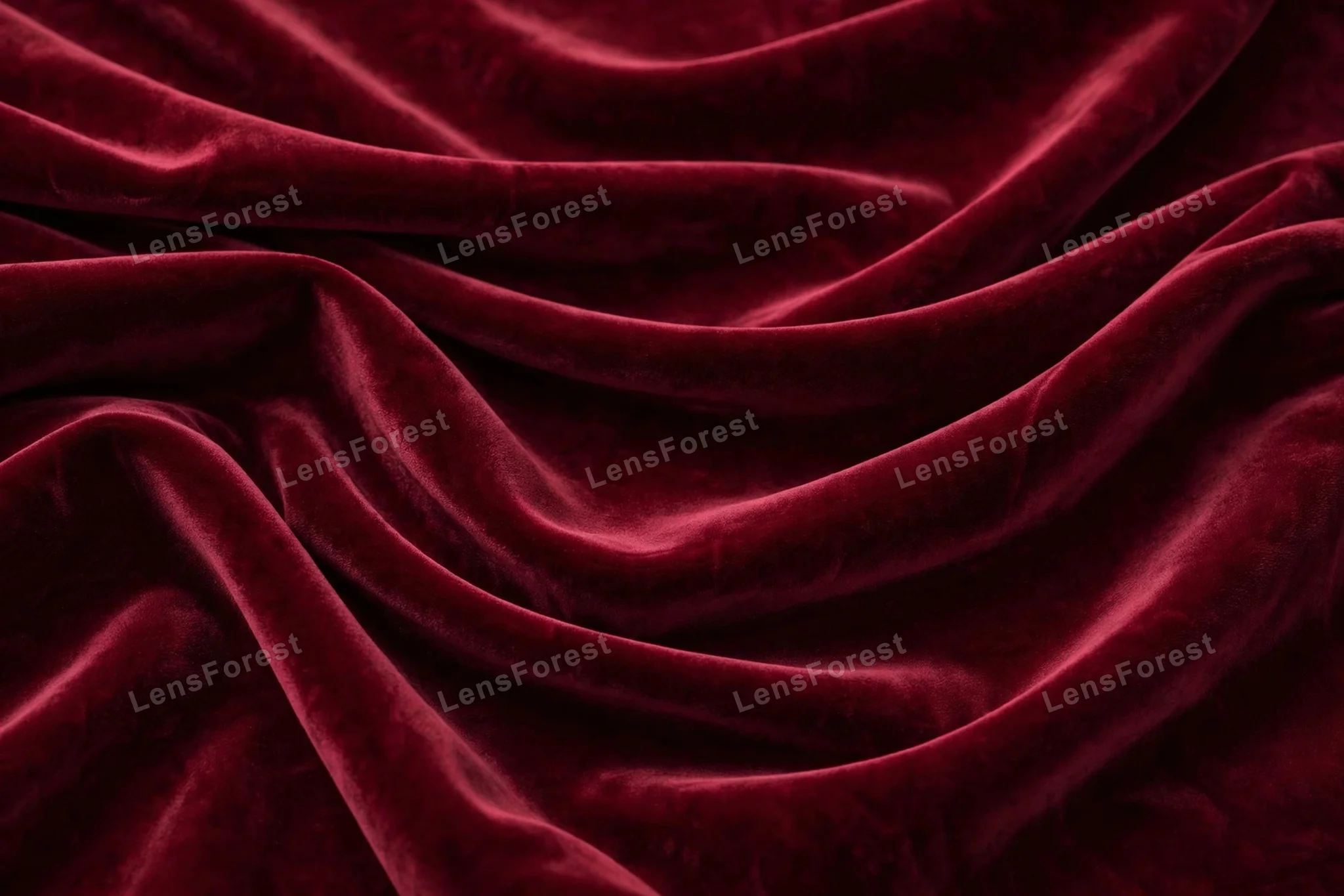A rich burgundy velvet fabric texture background with soft folds and a luxurious sheen